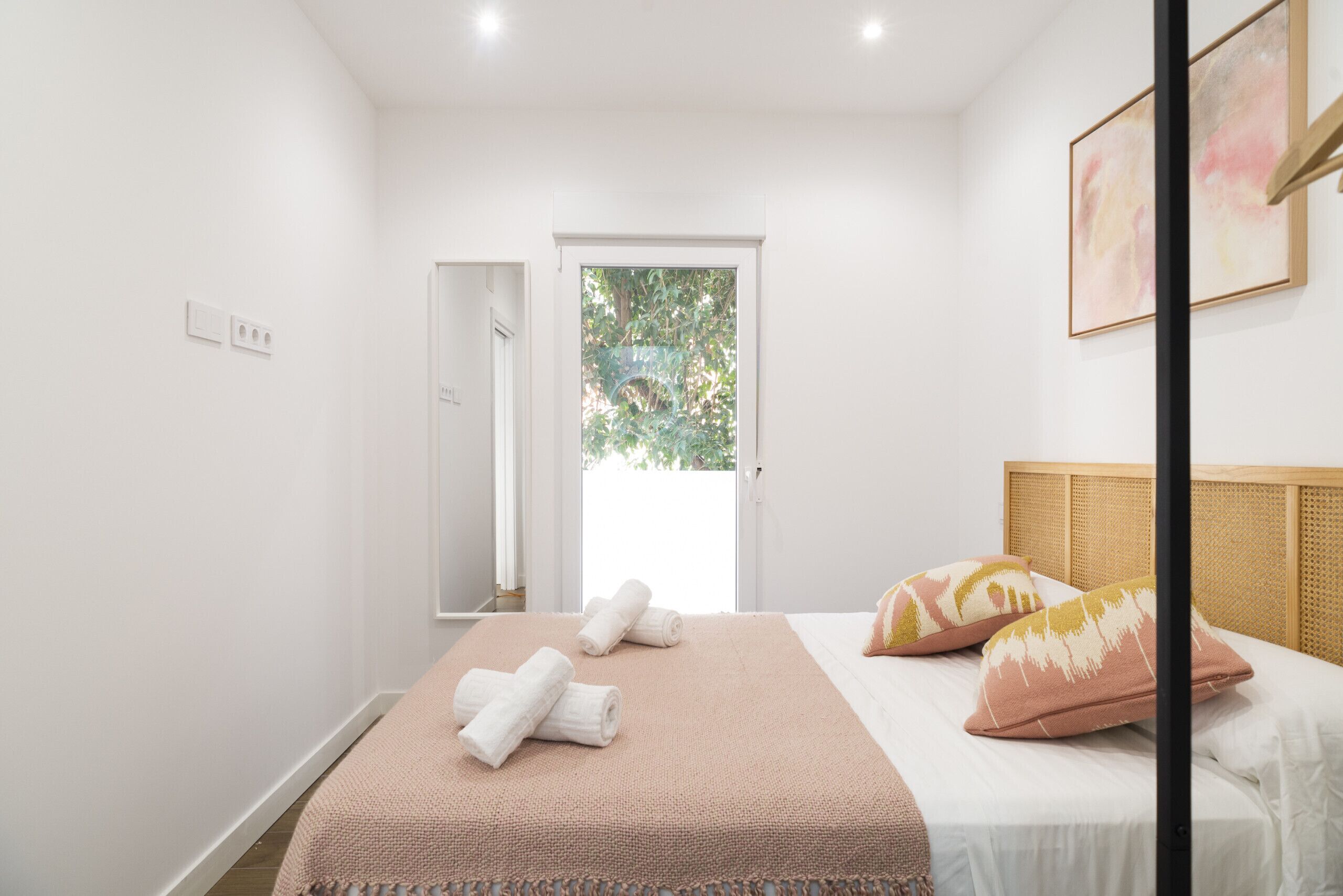 Een slaapkamer met een bed, een deur naar buiten en een raam.