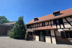A traditional half-timbered building with a gravel courtyard and a Christmas tree. - Gîte 1807 - Alsace of Yesterday & Today (Hangenbieten)
