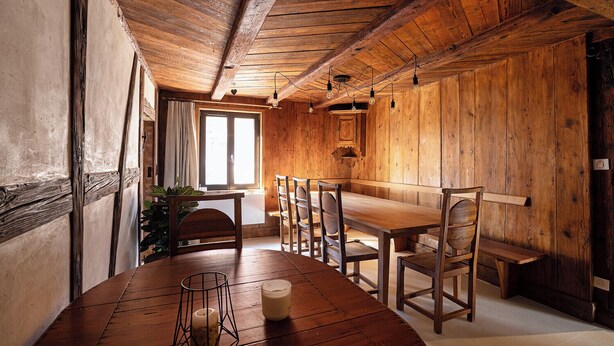 Un'area pranzo in legno con un tavolo lungo, sedie e una candela sopra il tavolo.