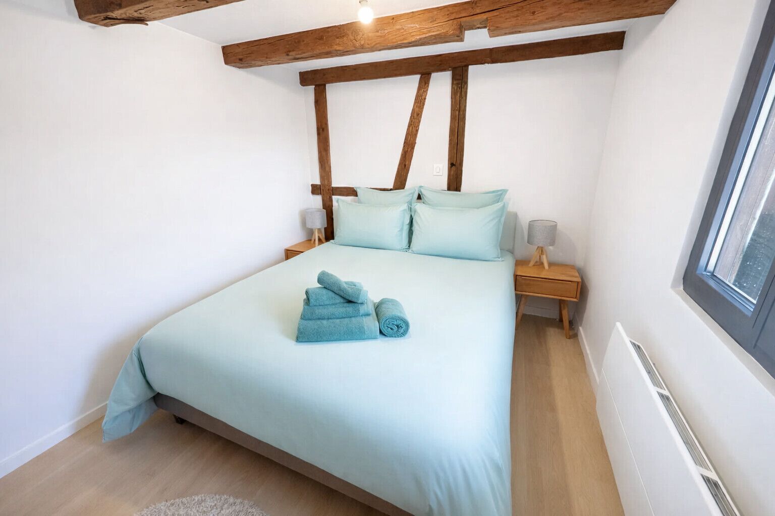Une chambre à coucher avec un lit, une tête de lit en bois, des tables de chevet et une fenêtre.