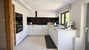 Una cucina moderna con mobili bianchi, una schiena di cucina nera e una finestra che offre luce naturale.