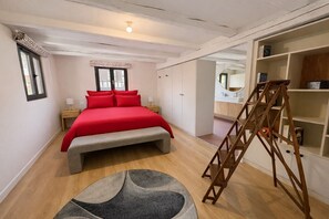 A bedroom with a bed, a bench, a ladder, a small rug, and a bookshelf.