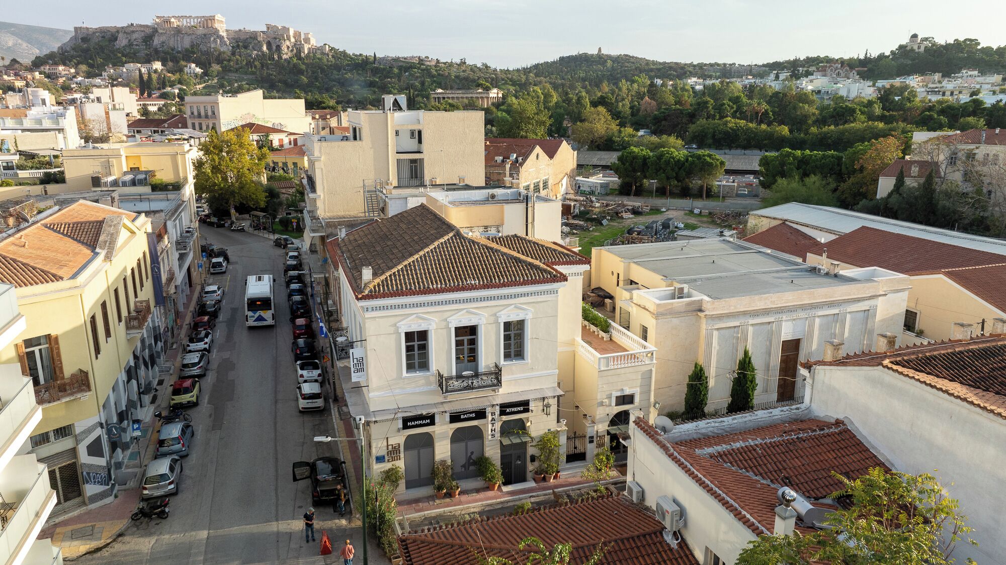 Vista de una calle en un pueblo con edificios, un autobús y coches estacionados.