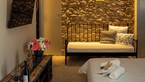 Ein Schlafzimmer mit Stehwand, einem Bett, einem Nachttisch, einer Vase mit Blumen und einer Weinflasche.