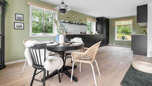 Una cocina moderna con comedor, ventanas amplias y vistas a la vegetación.