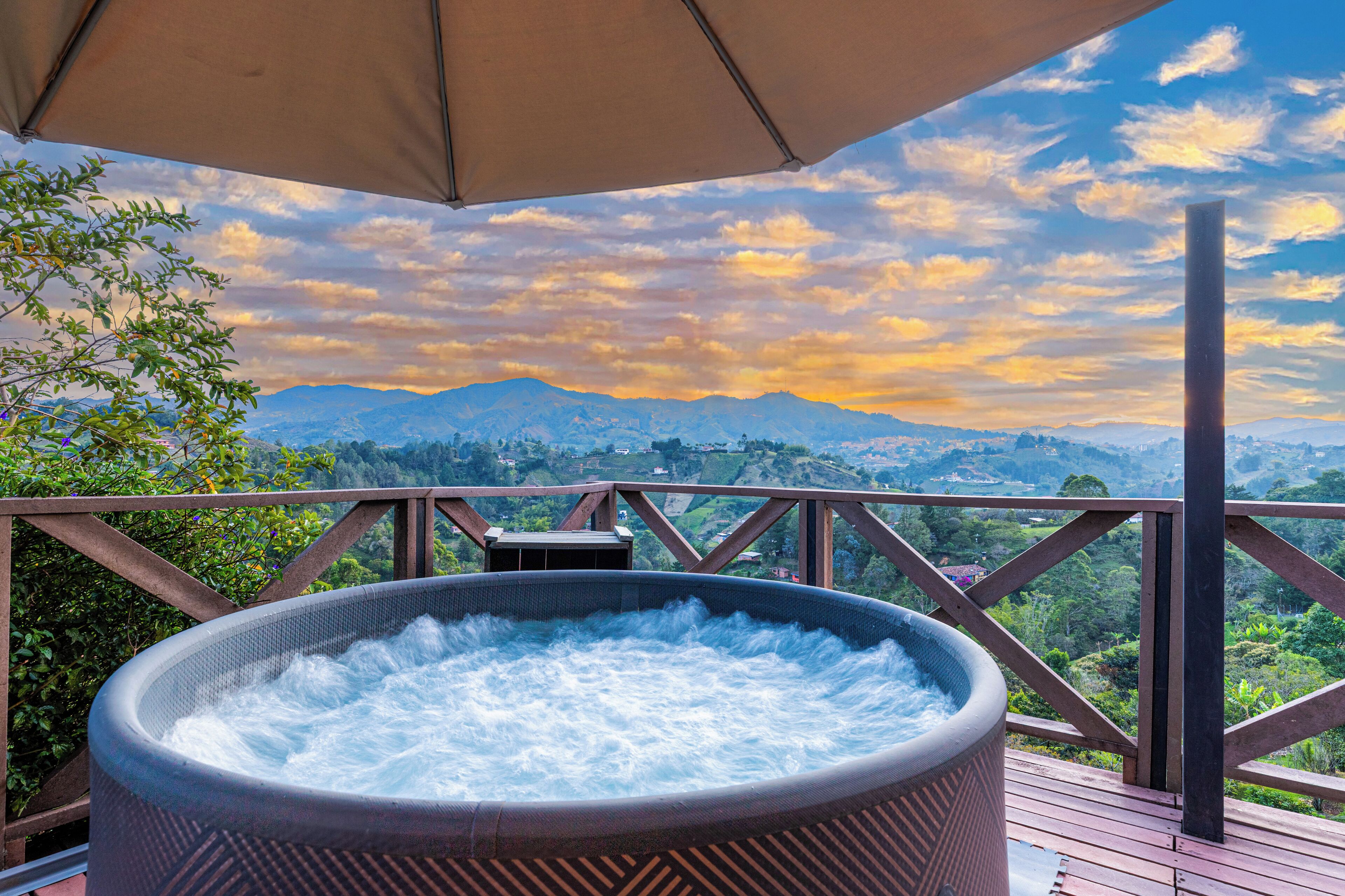 Uma banheira de hidromassagem em um deck de madeira com vista panorâmica para as montanhas.
