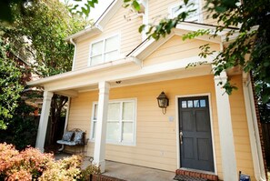 A two-story house with a porch, a front door, and a small garden area.