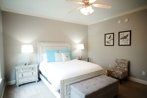 A bedroom with a bed, two bedside tables with lamps, a chair, and a ceiling fan.