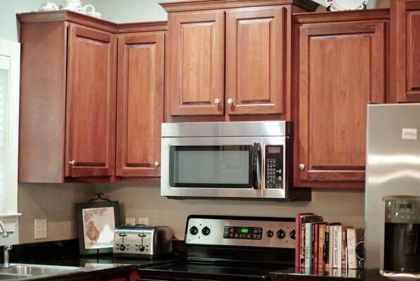 A kitchen with wooden cabinets, a stainless steel microwave, a toaster, and a stove.