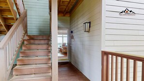 Un escalier en bois mène à une pièce d’où l’on a vue sur l’extérieur.