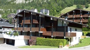 Un immeuble à plusieurs étages, doté de balcons, qui se dresse sur fond de montagnes.