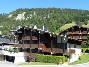 Un edificio de varios pisos con balcones, con montañas al fondo.