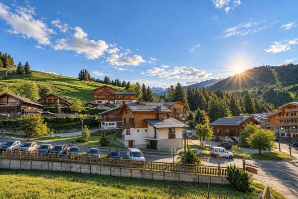 A mountain resort with wooden buildings, a parking area, and a view of the surrounding hills and mountains.