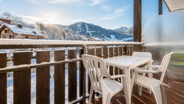 Un balcon avec vue sur des montagnes et des maisons enneigées.