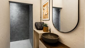 Ein modernes Badezimmer mit großem Spiegel, einer Holzauskładung, einem Waschbecken und einem gerahmten Kunstwerk über dem Spiegel.