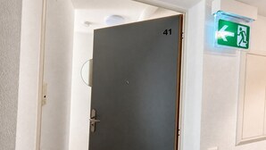 A closed door with the number 41, an emergency exit sign above it, and a light switch on the wall. - Charming Riverside Studio - Stork 41 (Zürich)