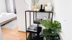 Une chambre d’hôtel avec un lit, une table d’appoint en métal noir avec un miroir, et une plante en pot.