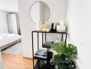 A hotel room with a bed, a black metal side table with a mirror, and a potted plant. - Charming Riverside Studio - Stork 41 (Zürich)