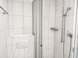 A shower area with a glass door, a handheld showerhead, a wall-mounted control panel, and a towel rack. - Charming Riverside Studio - Stork 41 (Zürich)