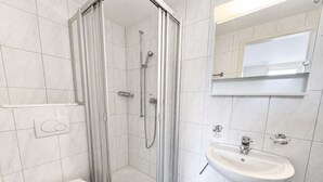 Une salle de bain moderne avec une douche à parois de verre, des toilettes blanches et un lavabo sur colonne.