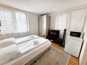 A hotel room with a bed, a TV, a microwave, and a refrigerator. - Charming Riverside Studio - Stork 41 (Zürich)