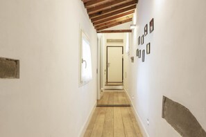 A narrow hallway with wooden flooring, white walls, and a door at the end. - Santa Maria Novella Top Floor Hideaway (Firenze)
