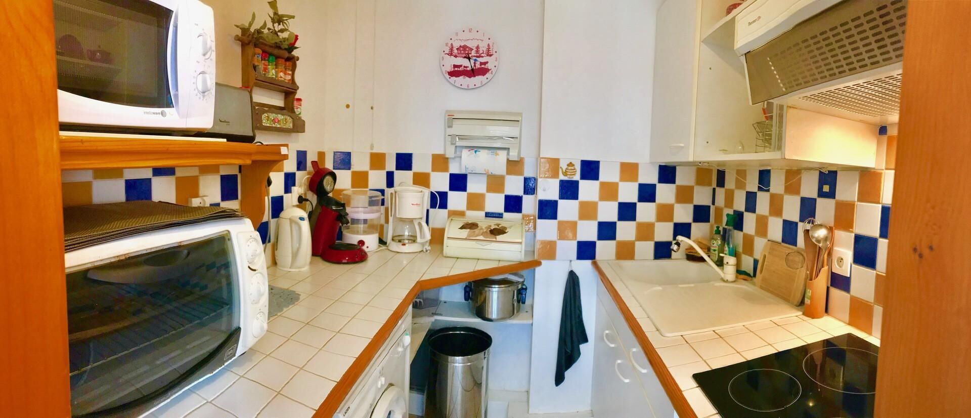 A compact kitchen with a microwave, toaster, kettle, and a sink.
