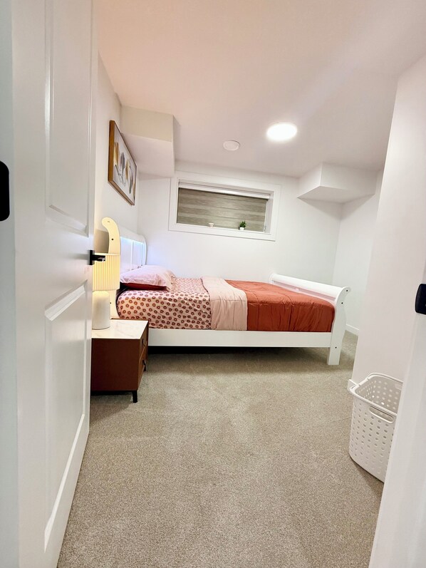 Un dormitorio con cama, mesita de noche, lámpara y ventana con vistas.