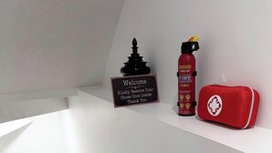 A white wall with a welcome sign, a fire extinguisher, and a red first aid kit. - Cozy 2 Bedroom Suite Close to Amenities (Edmonton)