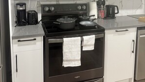 A modern kitchen with white cabinets, a stainless steel microwave, a black stove, and a built-in oven. - Cozy 2 Bedroom Suite Close to Amenities (Edmonton)
