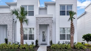 A modern two-story building with a white exterior, a stone accent wall, and a front door.