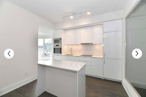 Cozinha moderna com armários brancos, uma ilha central e vista para a cidade.