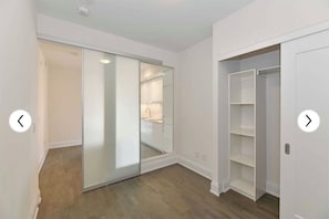 Um closet espaçoso com portas de correr, uma porta espelhada e prateleiras embutidas.