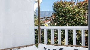 A white outdoor sofa with striped cushions, a wooden pergola, and a white railing.