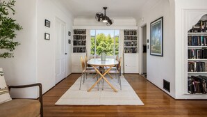 A dining area with a round table, chairs, and a white rug. There are bookshelves on either side of the room, filled with books.