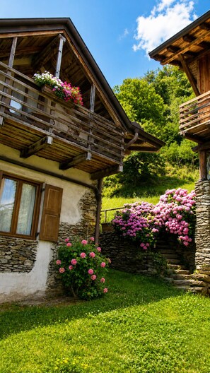 A traditional chalet with a stone facade, wooden balconies, and a lush garden.