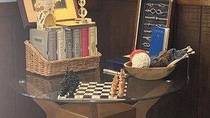 A corner room with a glass-top table, a chessboard, a lamp, a framed picture, and a bookshelf. - Beautiful accommodation for a peaceful stay, close to W.E.C. Gainesville, Ocala. (Citra)