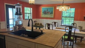 A kitchen with a central island, a sink, and a dining area with chairs and a table. - Beautiful accommodation for a peaceful stay, close to W.E.C. Gainesville, Ocala. (Citra)
