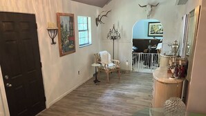 A room with a wooden floor, a white chair, a glass table, and a door. - Beautiful accommodation for a peaceful stay, close to W.E.C. Gainesville, Ocala. (Citra)