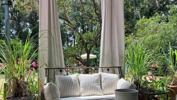 A garden with a swing chair, potted plants, and a glass table. - Beautiful accommodation for a peaceful stay, close to W.E.C. Gainesville, Ocala. (Citra)