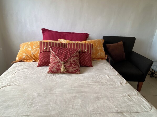 A bed with a white bedspread and multiple decorative pillows in various patterns and colors.