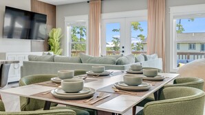Un salon moderne avec un coin repas, de grandes fenêtres et un ventilateur de plafond.