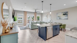 A modern kitchen with a central island, built-in appliances, and pendant lighting.