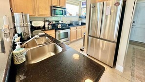 A kitchen with wooden cabinets, stainless steel appliances, a double sink, and a refrigerator.