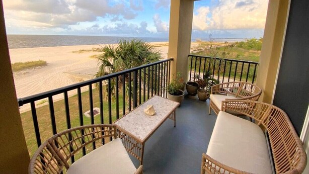 A balcony with wicker furniture, a table, and potted plants.