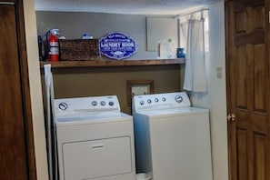 A laundry room with two washing machines, a fire extinguisher, and a self-service laundry sign.