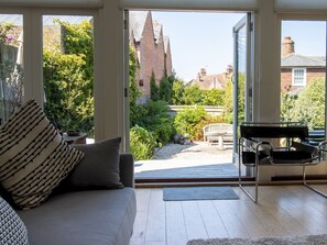 A modern living room with a sofa, a bench, and a piano. - The Studio House-Design & Garden | Pass The Keys (Rye)
