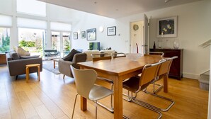 Un salon moderne avec un coin repas, de grandes fenêtres et un escalier.