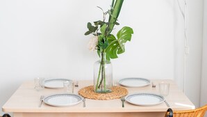 A dining table set with plates, cutlery, and a vase with flowers.