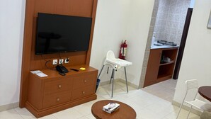 A modern living room with a flat-screen TV, wooden cabinet, and a round coffee table.